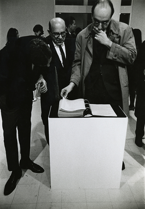 two men looking at a binder in an exhibition